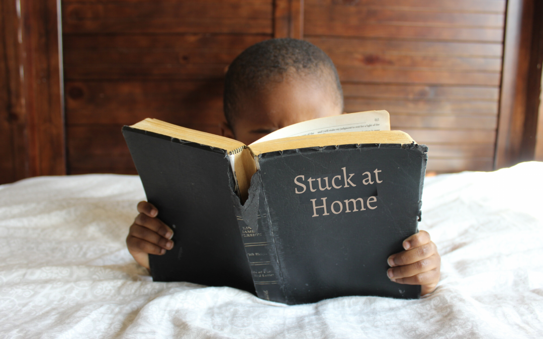 child reading "stuck at home" in bed