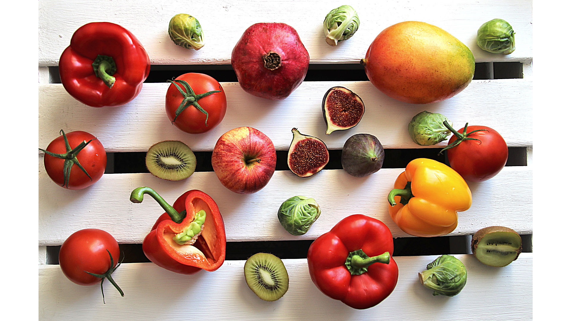 peppers, pomegranates, mangos, figs, and other fruit against a white background