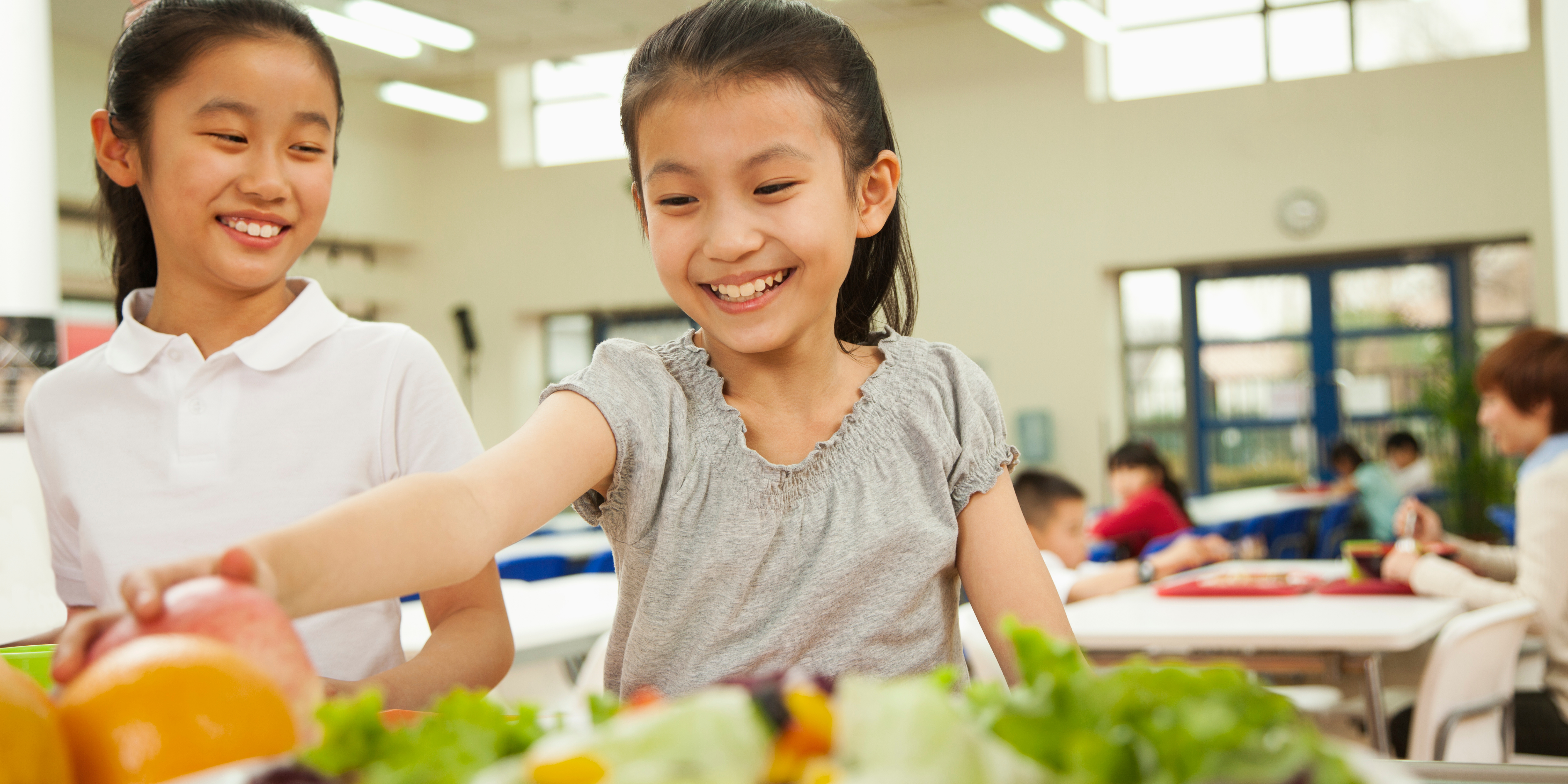 Two Asian girls selecting food in the school cafeteria